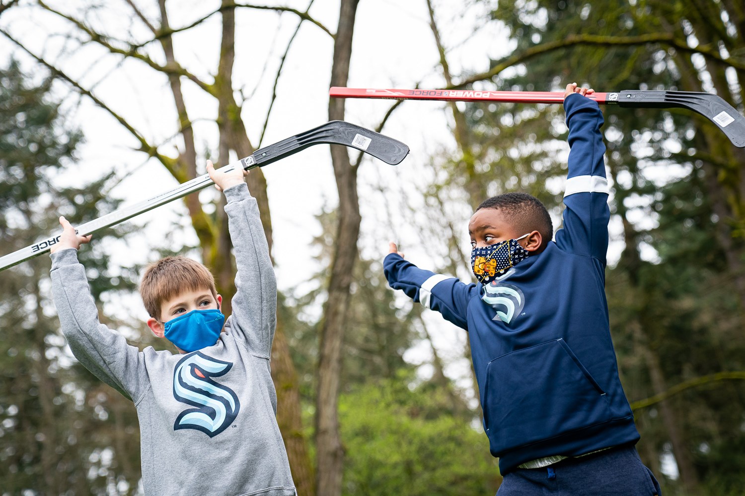 Kids raising hockey sticks